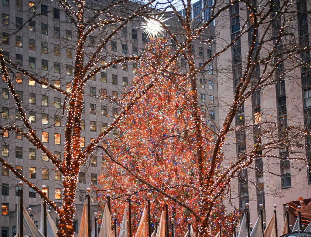 Crowd of people walking through Rockefeller Plaza with festive decorations