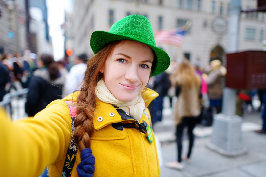 Young tourist taking a selfie with her smartphone during the annual St. Patrick's Day Parade on 5th Avenue in New York City