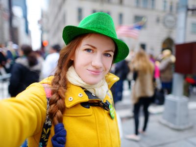 Young tourist taking a selfie with her smartphone during the annual St. Patrick's Day Parade on 5th Avenue in New York City