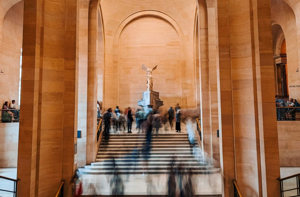 People on stairway in the Louvre near winged victory of samothrace statue