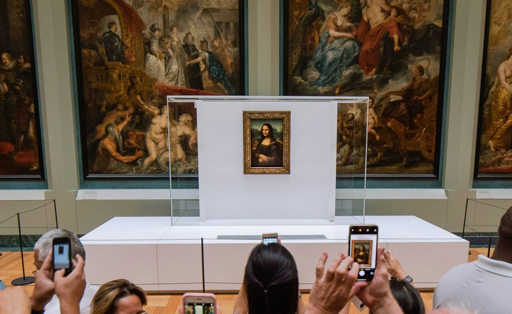 Tourists taking photos of the Mona Lisa in the Louvre Museum