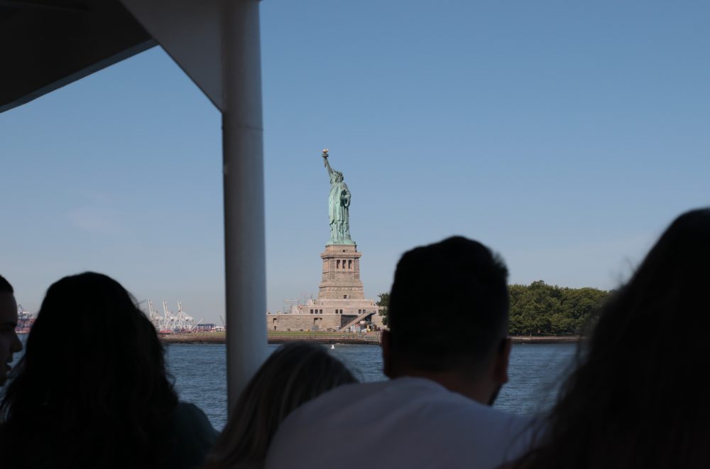 View of Statue of Liberty on cruise behind guests during NYC statue of liberty tour