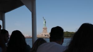 View of Statue of Liberty on cruise behind guests during NYC statue of liberty tour