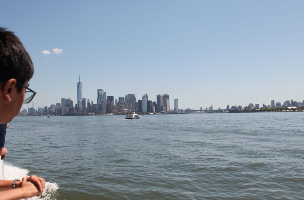 Young man looking at New York City skyline from Statue of Liberty cruise