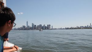 Young man looking at New York City skyline from Statue of Liberty cruise