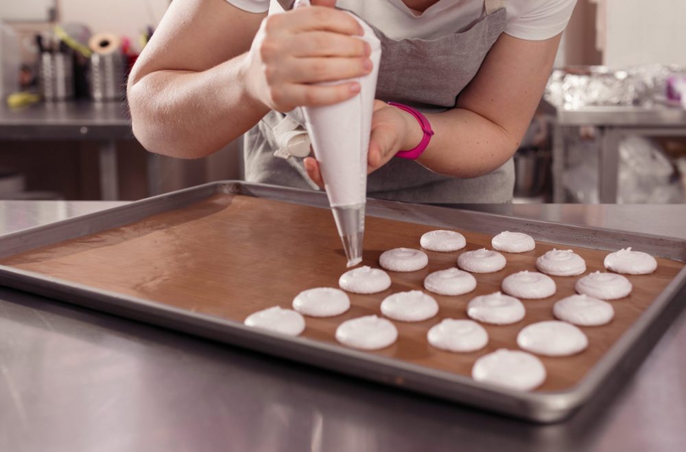 Woman piping macarons on baking tray in Paris Macaron baking class