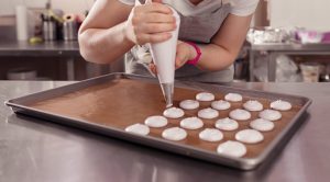 Woman piping macarons on baking tray in Paris Macaron baking class