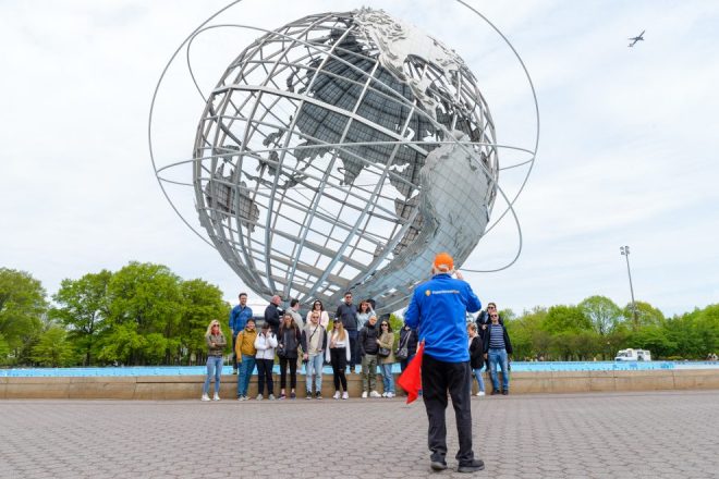 Tour guide taking a photo of the Unisphere on an NYC bus tour